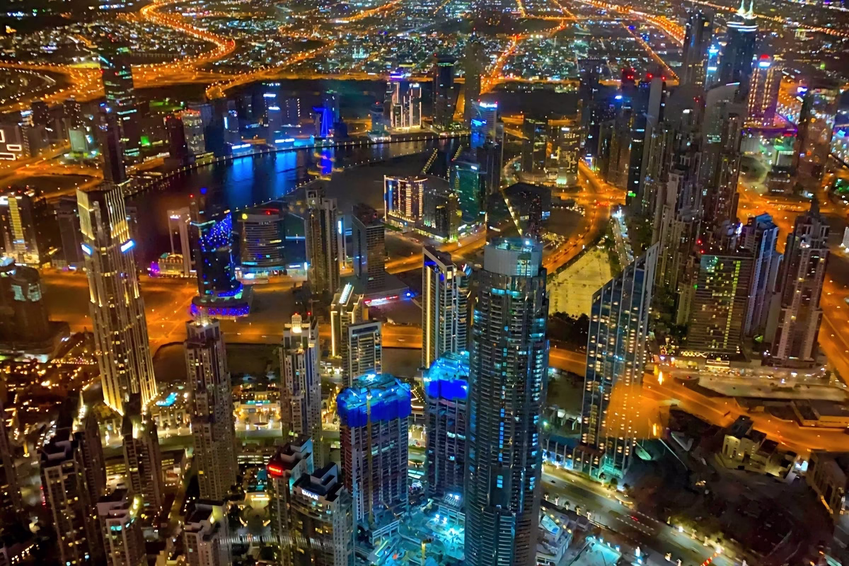 "Aerial view at night of International City Dubai with illuminated roads and residential clusters lit up in the dark"